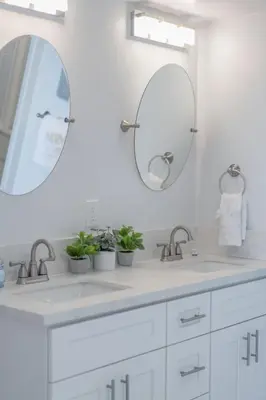 a white bathroom with two sinks and two mirrors at Oceanfront Studio in Heart of La Jolla Cove in San Diego
