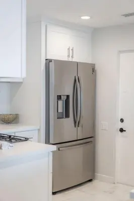a stainless steel refrigerator in a white kitchen at Oceanfront Studio in Heart of La Jolla Cove in San Diego