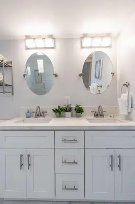 a white bathroom with two sinks and two mirrors at Oceanfront Studio in Heart of La Jolla Cove in San Diego