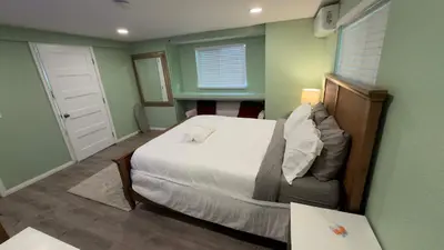 a bedroom with a white bed and a green wall at Walking Distance to Little Italy in San Diego