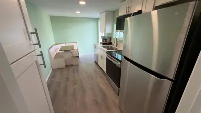 a kitchen with a stainless steel refrigerator and wooden floors at Walking Distance to Little Italy in San Diego