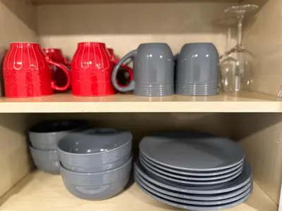 a shelf filled with plates and red cups and dishes at Walking Distance to Little Italy in San Diego