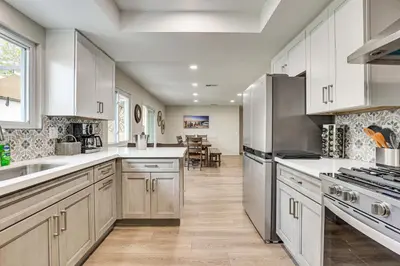 a kitchen with white cabinets and stainless steel appliances at Sunny Oceanside Home with Patio, 5 Mi to Downtown! in Oceanside