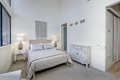 a white bedroom with a bed and a dresser at Oceanfront, Luxury Remodel, Pool, Walk To Dining in Encinitas