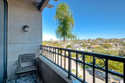 a balcony with a bench and a palm tree at Oceanfront, Luxury Remodel, Pool, Walk To Dining in Encinitas