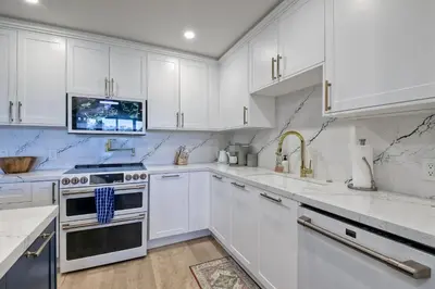 a white kitchen with white cabinets and a sink at Oceanfront, Luxury Remodel, Pool, Walk To Dining in Encinitas