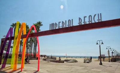 a large sign for the beach with people on the beach at IB Coastal Condo - Imperial Beach - Shops - Patio in Imperial Beach