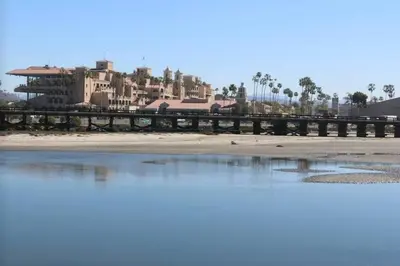 a bridge over the water in front of a building at Live the Beach Life in a Quaint Shell Cottage in Del Mar