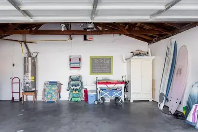 a garage with surfboards in it with a room with a table at Live the Beach Life in a Quaint Shell Cottage in Del Mar
