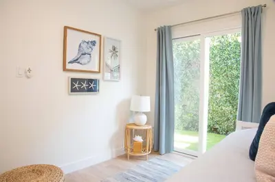 a bedroom with a bed and a sliding glass door at Live the Beach Life in a Quaint Shell Cottage in Del Mar