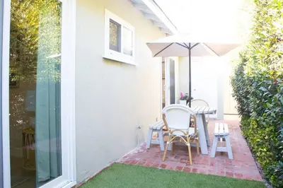 a patio with a table and an umbrella at Live the Beach Life in a Quaint Shell Cottage in Del Mar