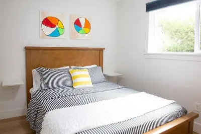 a bedroom with a bed and two paintings on the wall at Geometric Loft: renovated, hip, pets, pool/spa in Solana Beach