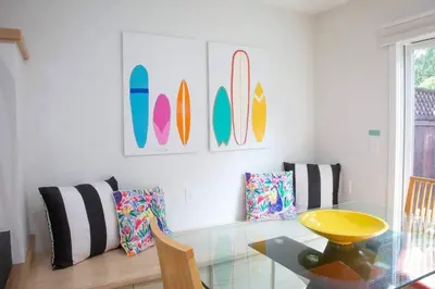 a dining room with a glass table and surfboards on the wall at Geometric Loft: renovated, hip, pets, pool/spa in Solana Beach
