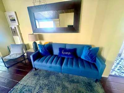 a blue couch in a living room with a mirror at Sunset Haven: Lakeside Charm in Ocean Beach in San Diego