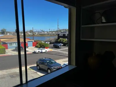 a window with a view of a parking lot with a car at Sunset Haven: Lakeside Charm in Ocean Beach in San Diego