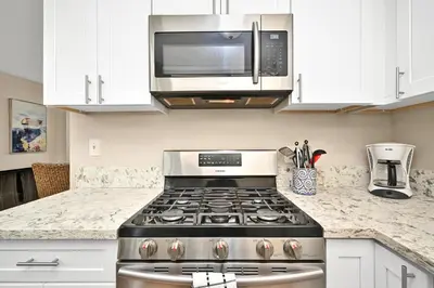 a kitchen with a stove and a microwave at Three Bedroom Three Bath Home w Patio 1 block from beach in Newport Beach