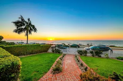 a view of the beach at sunset from a house at Oceanfront Dog Friendly Home with Waterfront Porch, Gas Grill, Hot Tub & Fire Pit in San Diego