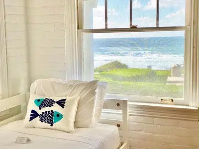 a bed with a pillow in front of a window at Oceanfront Dog Friendly Home with Waterfront Porch, Gas Grill, Hot Tub & Fire Pit in San Diego