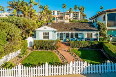 a white picket fence in front of a house at Oceanfront Dog Friendly Home with Waterfront Porch, Gas Grill, Hot Tub & Fire Pit in San Diego