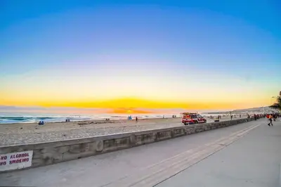 a view of the beach at sunset with a red truck at Sand & Sea in San Diego