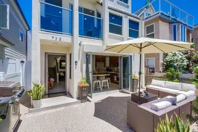a house with a patio with a couch and an umbrella at Sand & Sea in San Diego