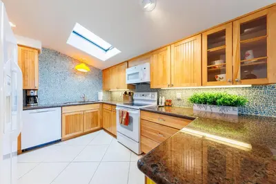 a kitchen with wooden cabinets and white appliances at SB-503 - Cali Surfer Lounge in Solana Beach