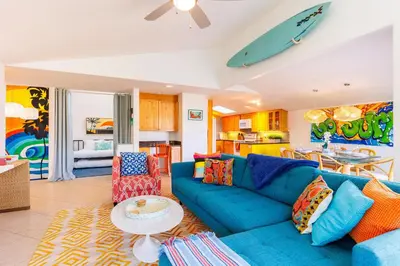 a living room with a blue couch and a surfboard on the wall at SB-503 - Cali Surfer Lounge in Solana Beach