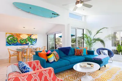 a living room with a blue couch and a surfboard on the wall at SB-503 - Cali Surfer Lounge in Solana Beach