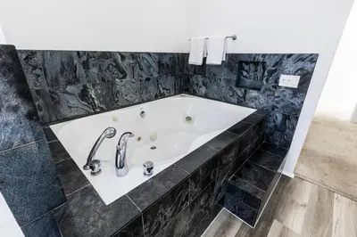 a bath tub in a bathroom with black marble at Elite Retreat! Hot Tub, Arcade, & Theater. 6 Beds! in Encinitas