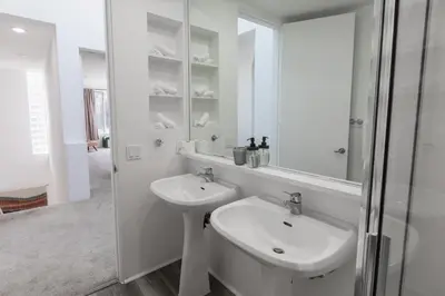 a white bathroom with a sink and a mirror at Elite Retreat! Hot Tub, Arcade, & Theater. 6 Beds! in Encinitas