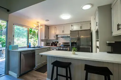 a kitchen with white cabinets and stainless steel appliances at Cozy Getaway. Fire Pit and Endless Views! 5 Beds in San Diego