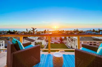 a balcony with chairs and a table with the sunset at Seaside in Cardiff-by-the-Sea