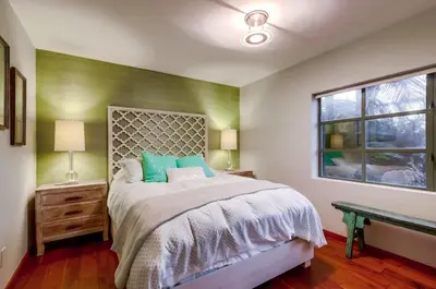 a bedroom with a bed with green walls and a window at Seaside in Cardiff-by-the-Sea