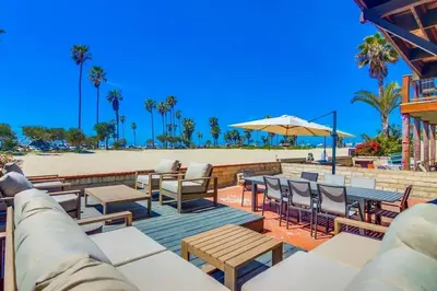 a patio with tables and chairs and a beach at Jetty View 1 in San Diego