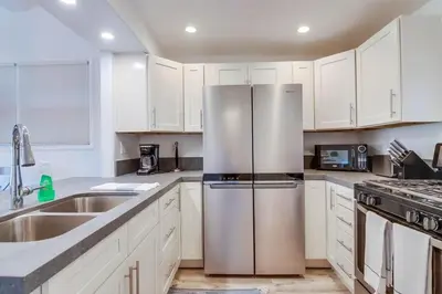 a kitchen with white cabinets and a stainless steel refrigerator at Jetty View 1 in San Diego