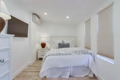 a white bedroom with a bed and a window at Jetty View 1 in San Diego