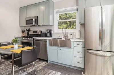 a kitchen with white cabinets and a table and a refrigerator at One bedroom retreat full kitchen/laundry 1GB Wi-Fi in Bonita