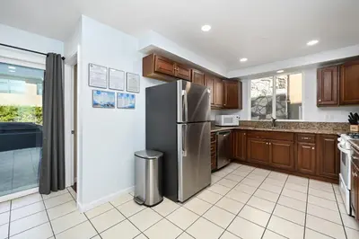 a kitchen with a stainless steel refrigerator and wooden cabinets at 4 bedroom home with Patio 10 seconds from the Sand in Newport Beach