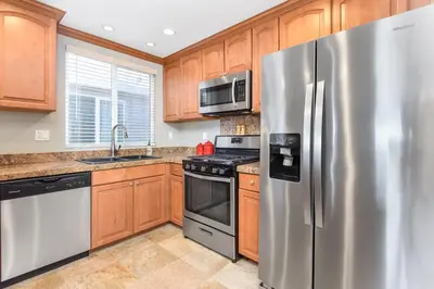 a kitchen with stainless steel appliances and wooden cabinets at 4 Bedroom Home Steps from the Sand with Balcony & BBQ in Newport Beach