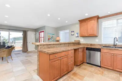 a kitchen with wooden cabinets and a counter top at 4 Bedroom Home Steps from the Sand with Balcony & BBQ in Newport Beach