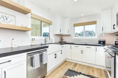 a kitchen with white cabinets and black counter tops at BRAND NEW Luxury 1 Bedroom Condo Steps from the Beach in Newport Beach