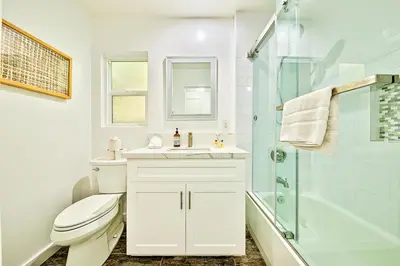 a white bathroom with a toilet and a shower at 6 Bedroom Home with Rooftop Deck Between the Bay & the Beach in Newport Beach