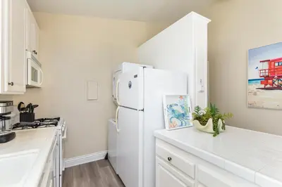 a white kitchen with a white refrigerator in a kitchen at 2 Bedroom in BACK of our BEACHFRONT Home in Newport Beach