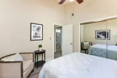 a bedroom with a bed and a chair and a mirror at 2 Bedroom in BACK of our BEACHFRONT Home in Newport Beach