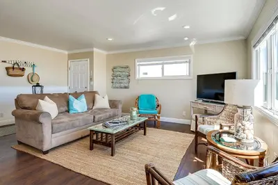 a living room with a couch and a tv at Beachfront Getaway on the Sand in Newport Beach