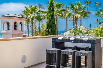 a table on a balcony with palm trees at Mediterranean Beauty with Rooftop Deck and Views in San Diego