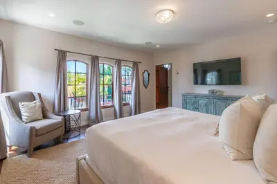 a bedroom with a large white bed and a chair at Mediterranean Beauty with Rooftop Deck and Views in San Diego