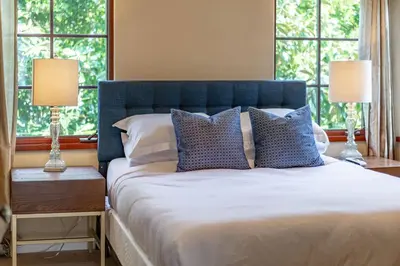 a bedroom with a bed with a blue headboard and windows at Mediterranean Beauty with Rooftop Deck and Views in San Diego