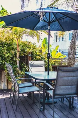 a table and chairs with an umbrella on a deck at Mission Beach Retreat Steps to Bay & Beach in San Diego