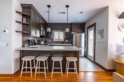 a kitchen with wooden cabinets and a counter with stools at Mission Beach Retreat Steps to Bay & Beach in San Diego